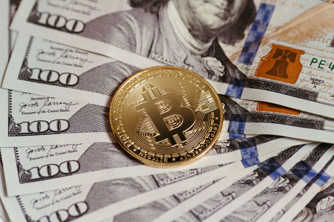 Home Gold Bitcoin coin resting on US dollar bills showcasing digital and traditional currency.