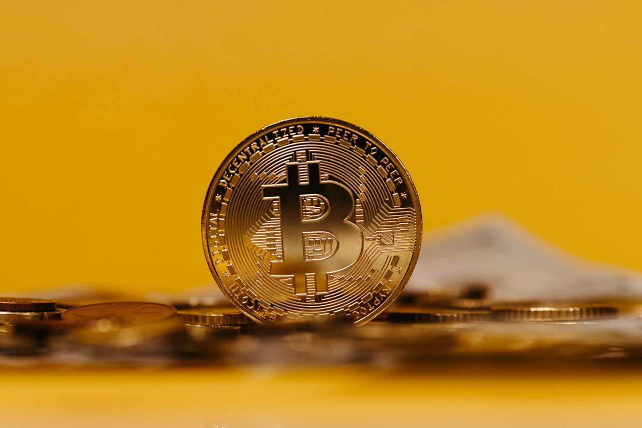 Home Close-up of a Bitcoin coin with a yellow background, representing cryptocurrency.