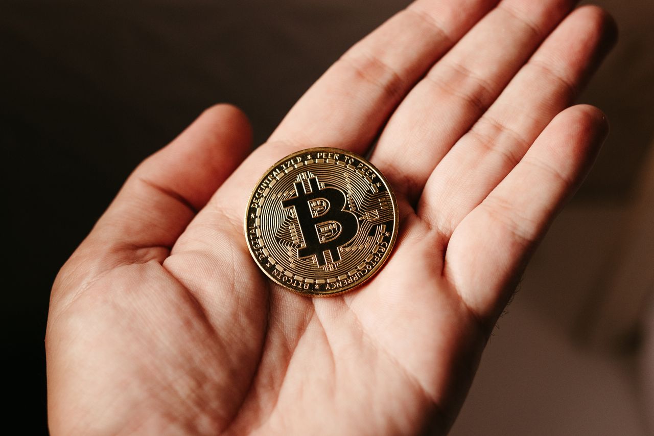 Home Close-up of a hand holding a Bitcoin coin, illustrating cryptocurrency concept.