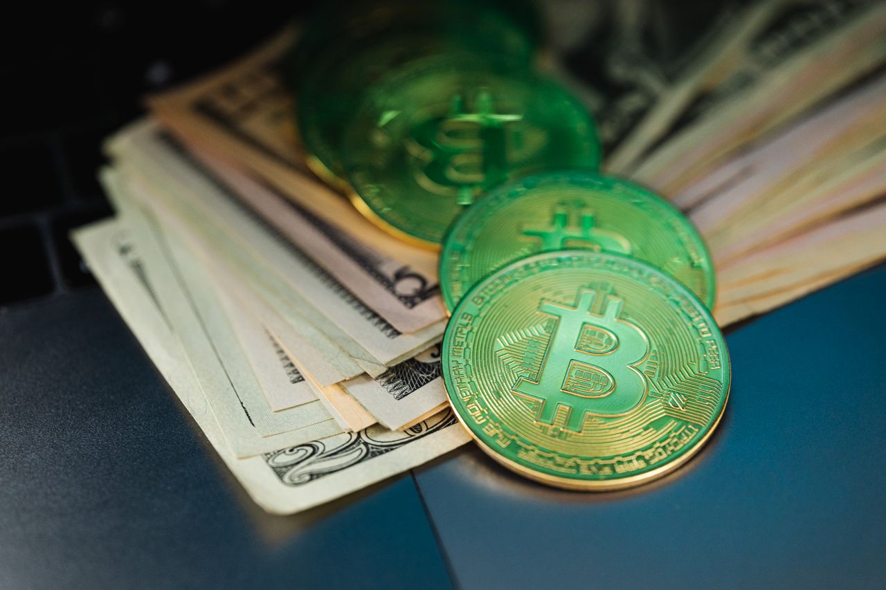Close-up of Bitcoin with US dollars symbolizing digital and paper currency.