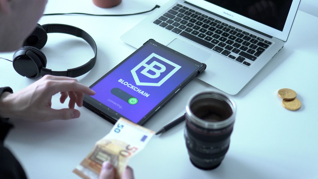 Home Close-up of digital currency transaction using blockchain technology on tablet with laptop and euro bills.